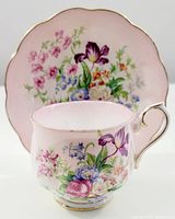 Photo of Royal Albert tea cup in front of matching floral saucer, showing pink blush inside cup rim and detailed floral design on both pieces.