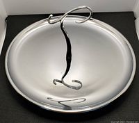 Front view of the chrome appetizer serving tray showing the circular tray and the curly center handle