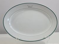 Full frontal view of the large oval vitrified serving platter showing the white surface and green rim line.