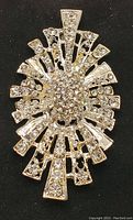 Close-up photo of the silver-tone hairpin accessory decorated with multiple clear rhinestones in a sunburst pattern.