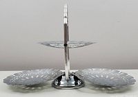 Side view of the three folding chrome serving dishes connected at the center with a handle, showing the dishes slightly elevated and spaced out.