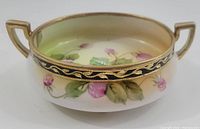 View of the side of the Nippon footed bowl showing one handle and floral decoration on exterior surface