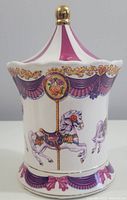 Front view of the ceramic cannister showing carousel horse design and striped lid.