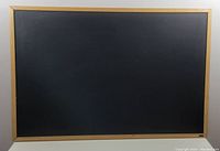 Front view of the chalk board showing the full black writing surface framed in oak wood