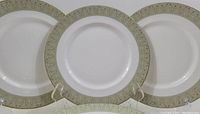 Seven Royal Doulton fine bone china dinner plates in Sonnet pattern with green and gold ornate border, arranged in a stack and displayed upright.
