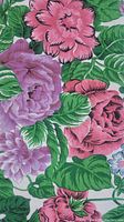 Close-up photo showing the detailed floral pattern of large pink and purple flowers with green leaves on white cotton fabric.