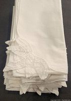 Stack of 7 white vintage dinner napkins folded, showing lace embroidered corners.