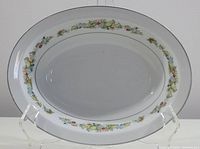 Full view of the oval serving bowl with fruit and leaf border pattern on white porcelain.