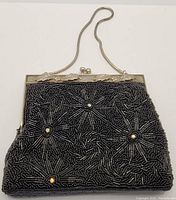 Front view of vintage evening bag showing detailed bead and sequin floral pattern with iridescent rhinestone centers. Ornate metal frame with leaf design and metal chain handle visible.