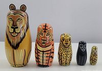 Five wooden hand-painted animal nesting dolls arranged in size order, lion being largest, smallest resembling a monkey.