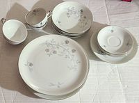Full view of the china set including plates, bowls, cups, and saucers laid out on white surface