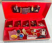 Full overview of vintage cufflinks and money clips arranged inside red velvet lined case with compartments and black leather strip for holding some clips
