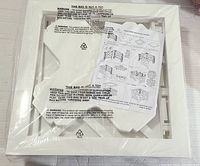 Flat packed parts of the white wooden planter box holder with assembly instructions on top.