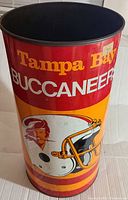 Full view of the metal trash can showing Tampa Bay Buccaneers text and helmet logo