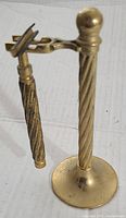 Photo of vintage solid brass barber razor hanging on its matching twisted brass stand with round flat base.