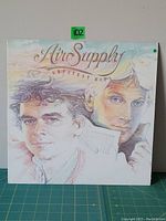 Front cover of Air Supply Greatest Hits vinyl LP showing illustrated portraits of the band members in pastel colors