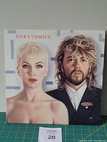 Front cover of Eurythmics Revenge vinyl LP album jacket featuring portrait of band members on light geometric background.