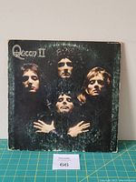 Front cover of Queen II vinyl LP showing four band members in dramatic portrait with noticeable wear on jacket edges and surface.
