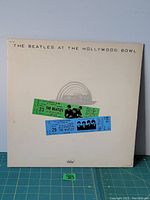 Front cover of 'The Beatles At The Hollywood Bowl' album jacket showing two colored concert tickets and Capitol logo.
