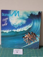 Front cover of Boney M. Oceans of Fantasy vinyl LP showing the band members surfing on a large ocean wave.