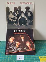 Two vinyl LPs by Queen: The Works and Greatest Hits shown with their jackets, both records lightly scratched, jackets in good condition.