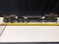 Full length profile of 4-piece cast iron train set with measuring tape showing approximately 20 inches long.