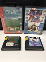 Four Sega Genesis game cartridges with two in cases (Pebble Beach Golf Links and NHLPA Hockey 93) and two loose cartridges (Rings of Power and NHL 95) placed upright on a flat surface.