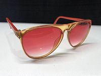 Side angled view showing translucent light brown to pink frame with pink gradient lenses and pink arms.