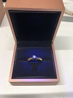 Ring displayed front-facing in a presentation box under blue-toned lighting