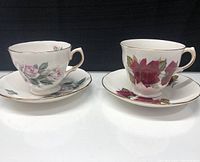 Two Royal Vale teacup and saucer sets with floral patterns placed side by side