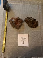 Two rock samples on fabric surface with tape measure showing size.