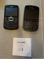 Photo shows BlackBerry Bold and LG keyboard cell phones side by side on a textured surface with a lot identification tag.