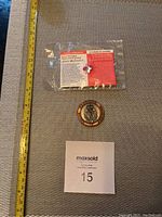 Full lot overview photo including military medallion, Remembrance Day pin in package, ruler for scale, and MaxSold lot number card.