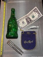Full view of all items including Buddha bottle, novelty bill, porcelain sign, Crown Royal bag, and nutcracker.