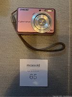 Front angled view of pink Sony Cyber-shot DSC-S930 camera on textured gray surface with wrist strap visible
