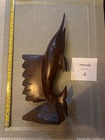 The full view of the dark brown mahogany swordfish statue with visible wood grain and an upright pose on a base, measuring approximately 16 inches tall.