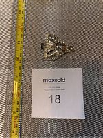 Top view of the silver-toned women's belt buckle with clear stones, showing approximate size with a measuring tape.
