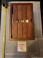 Top-down view of the wooden picture case showing four sliding panels with oval cut-outs, alongside a yellow measuring tape showing length approximately 14 inches.