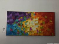 Full view of the abstract multicolor square pattern canvas painting hung on white wall.