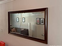 Mirror hanging on a living room wall reflecting furniture and decor