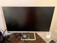 Front view of the HP 24-inch monitor on a wooden desk showing screen and silver stand.