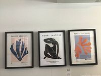 Three framed prints displayed side by side on wall