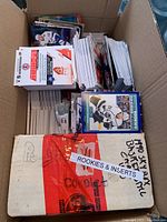 Open cardboard box showing large stacks of hockey trading cards including some labeled as rookies and inserts