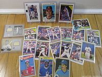 View of multiple baseball cards and memorabilia spread on floor, including game used bat cards and player rookie cards.