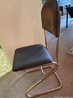 Side view showing tubular metal frame and fabric upholstered seat and backrest, with visible light wear and weathering on fabric.