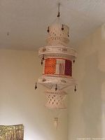 Front view of crochet lantern shade, highlighting orange and white woven section, cream crochet detailing, and bead tassels.