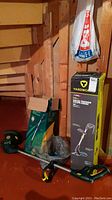 Two electric string trimmers shown by box and laid out in basement. Includes trimmer parts and replacement spool.