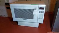 Front view of white Panasonic microwave showing keypad control panel and windowed door.