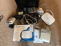 Lot showing three black Panasonic cordless phones with docking stations, a white Ooma Telo box and device, power adapters, and other networking devices scattered on carpet.