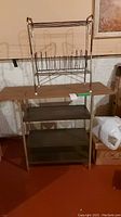 View of metal shelf unit with three shelves holding record holder stand on top, situated in basement with concrete floor and partially visible cardboard boxes.